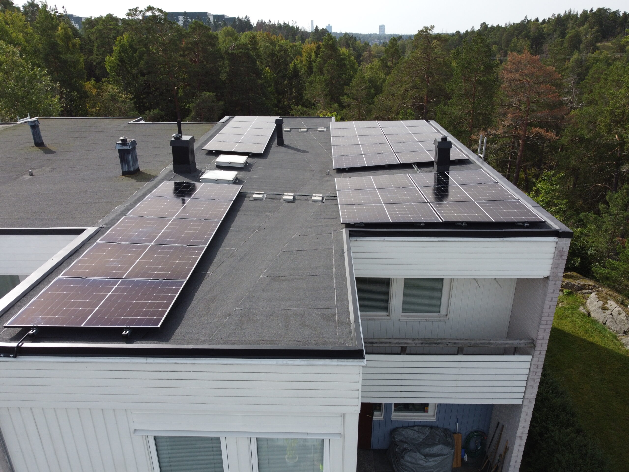 Fågelvy över taket på ett vit hus. Hustaket är gjort av takpapp och har 4 paneler av solceller.