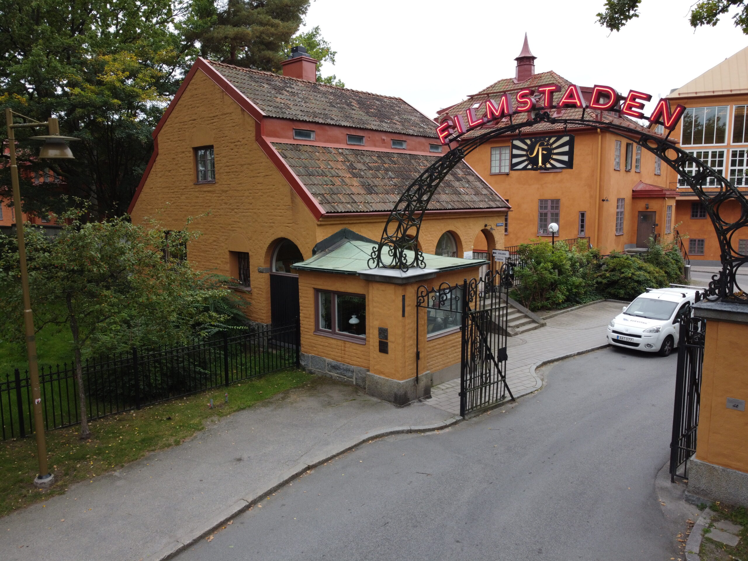 Fågelvy över et gult tegelhus och en grind med skylten "Filmstaden" på.