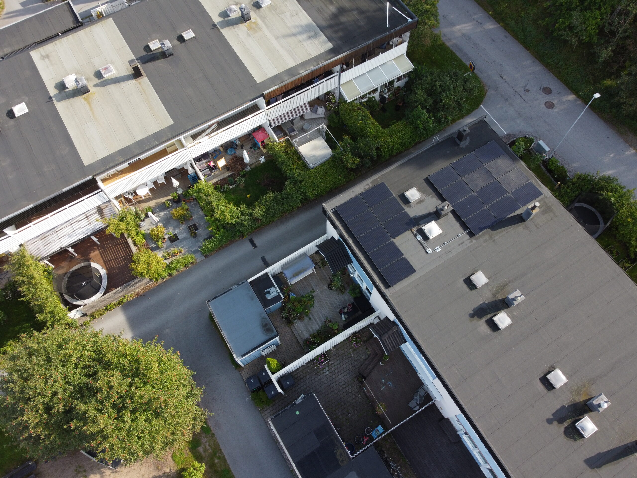 Ett radhusområde med platt papptak. På ett av husen sitter två paneler med solceller.