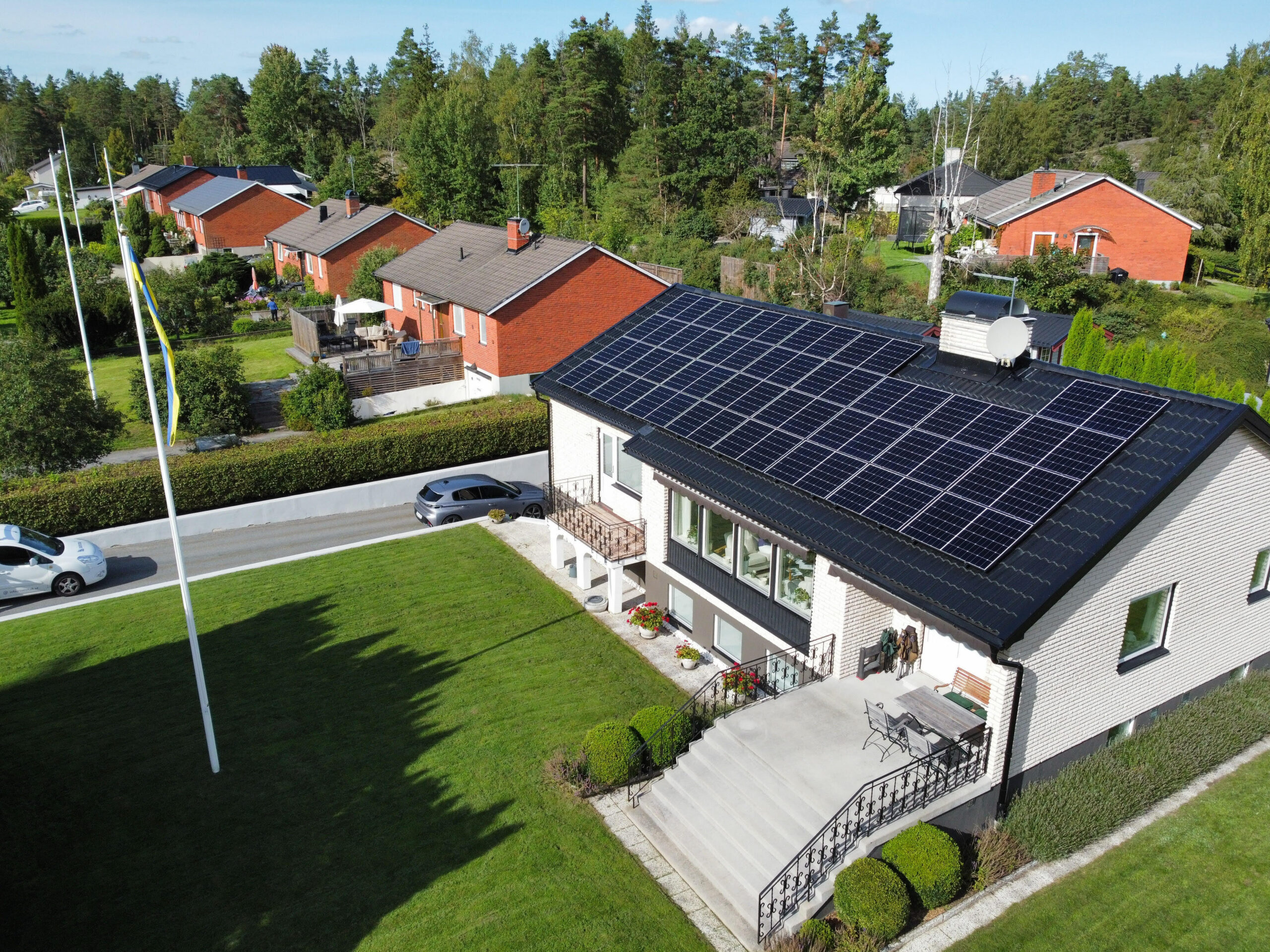 Fågelvy över ett hustak med solceller. Taket är gjort av svarta betongpannor, och har en skorsten samt takstege.