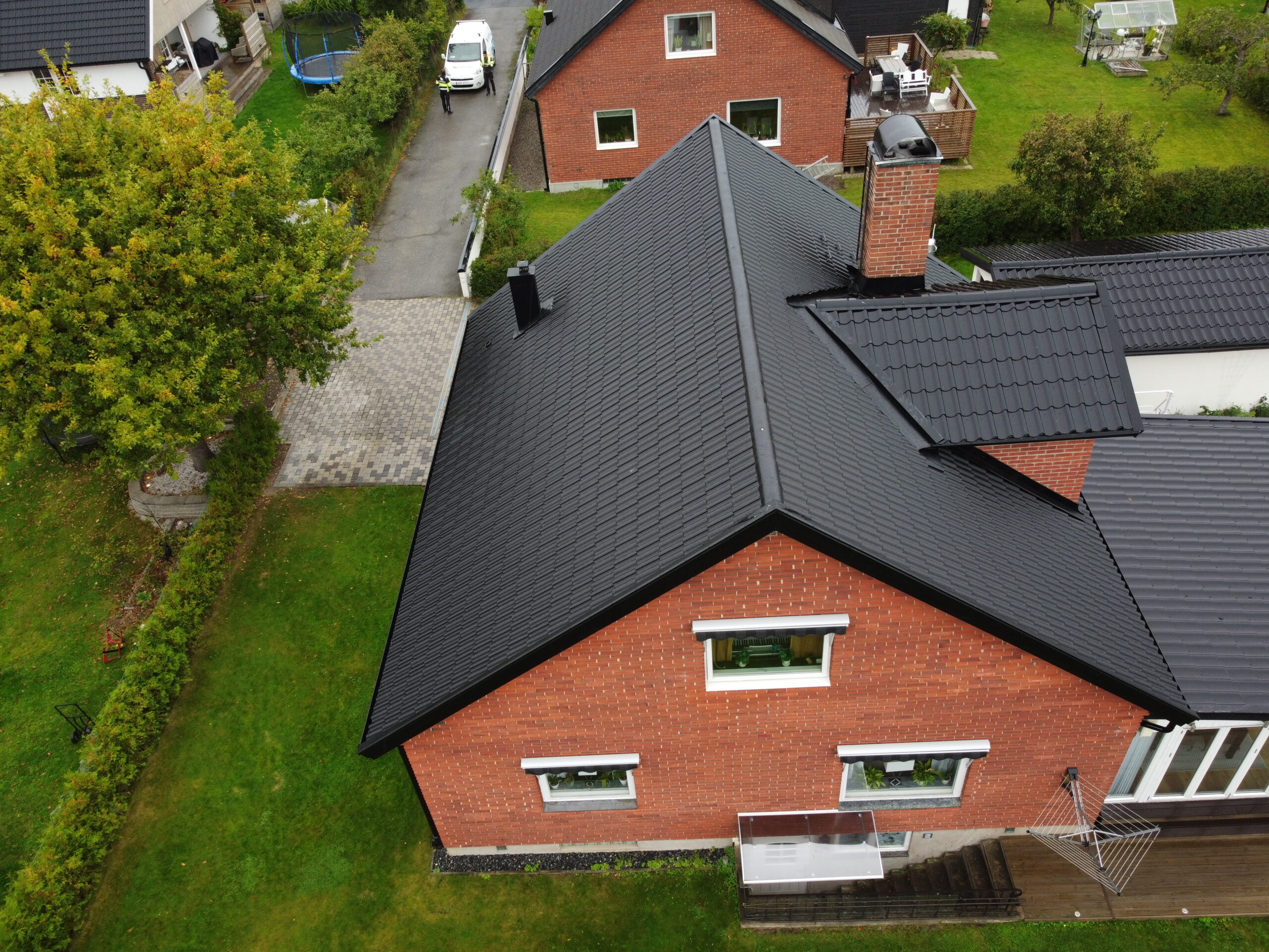 Fågelvy över ett tegelhus och hustaket gjort av betongpannor. På taket syns en skorsten av tegel.