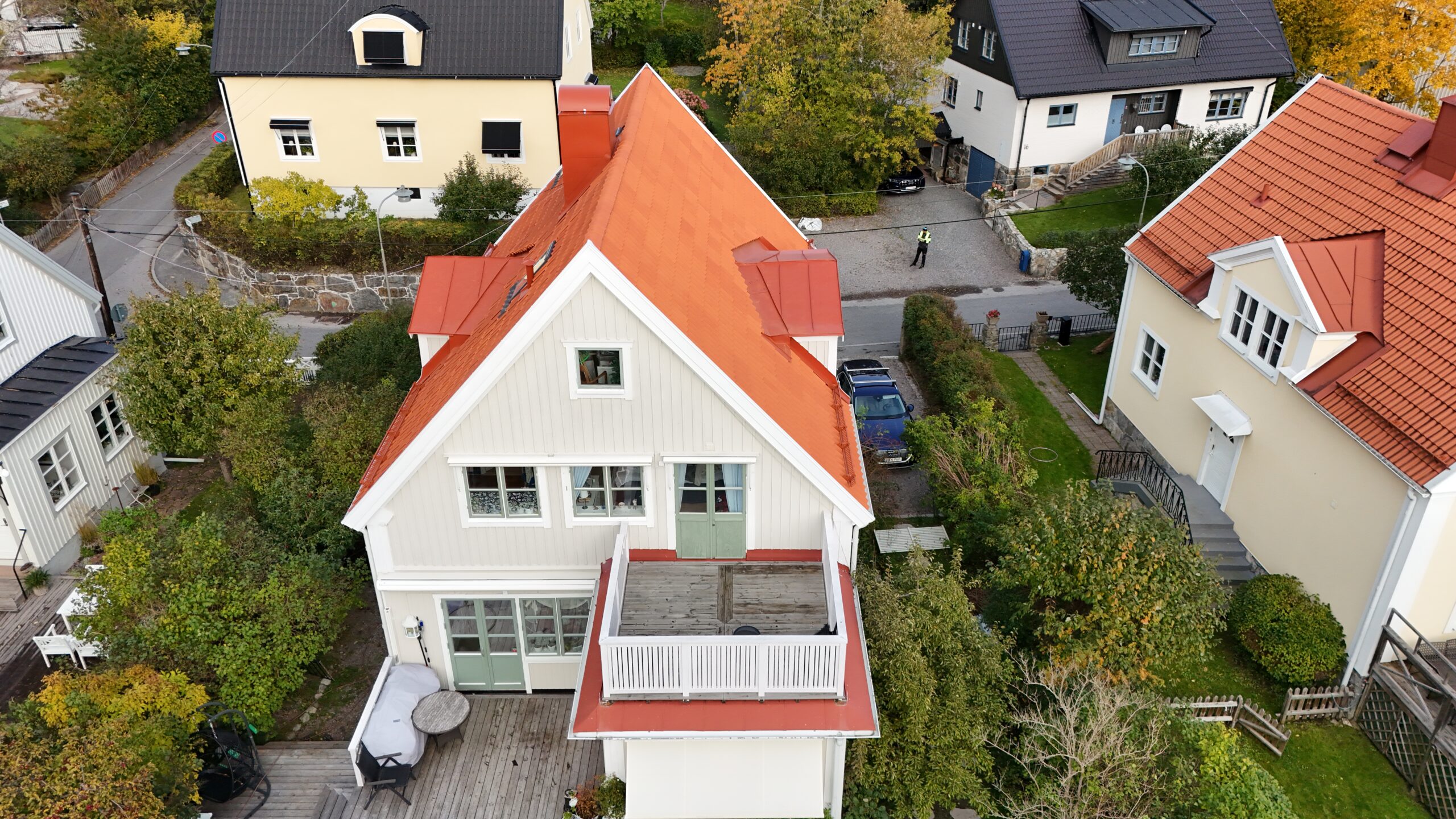 Fågelvy över ett villahus efter takomläggning. Taket är kombinerat med tegelpannor och bandtäckt plåt. I bakgrunden syns närliggande grannhus.