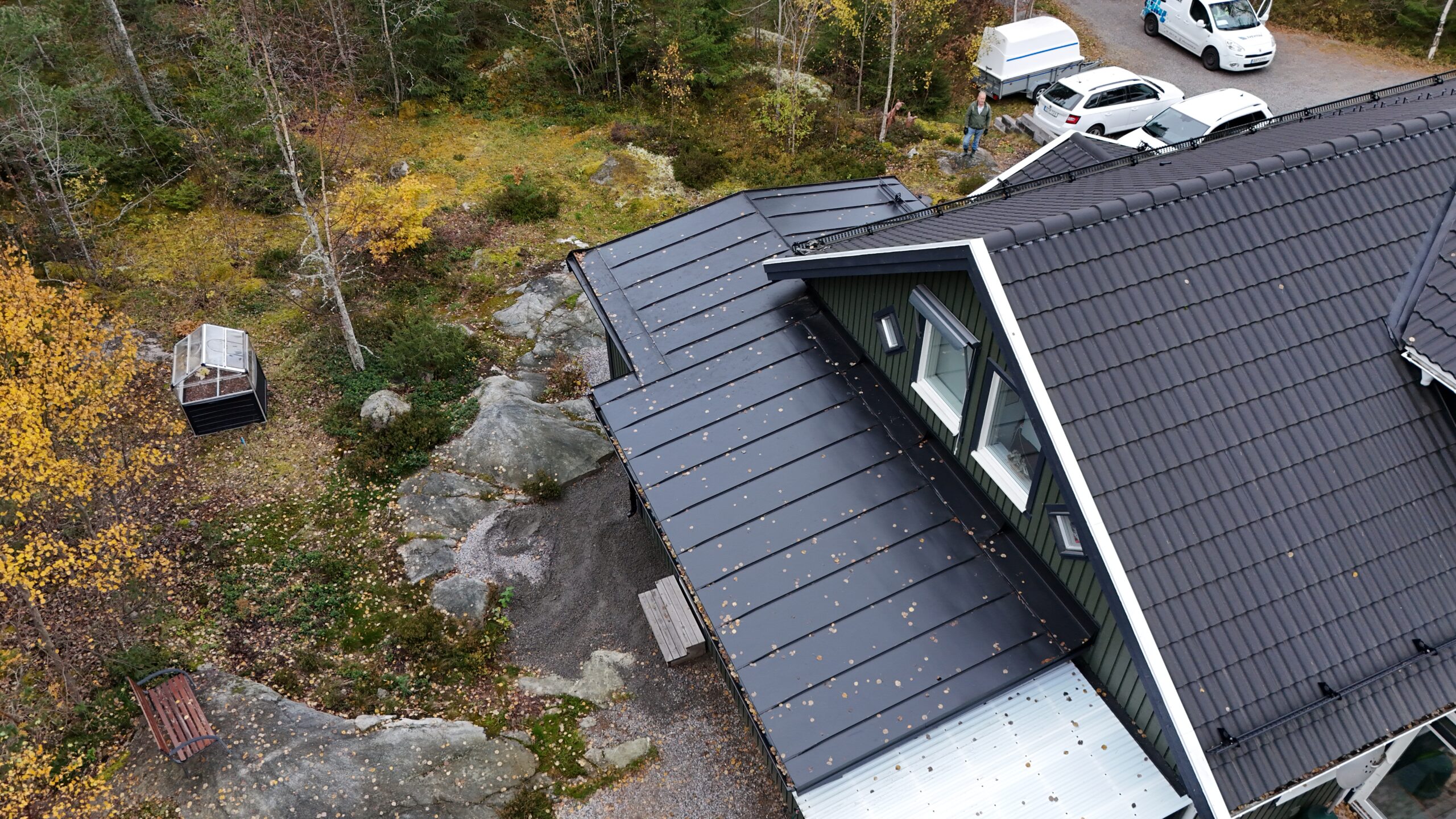 Ett villahus med sluttande hustak gjort av betongpannor och bandtäckt plåttak. På taket finns snörasskydd och takstege.