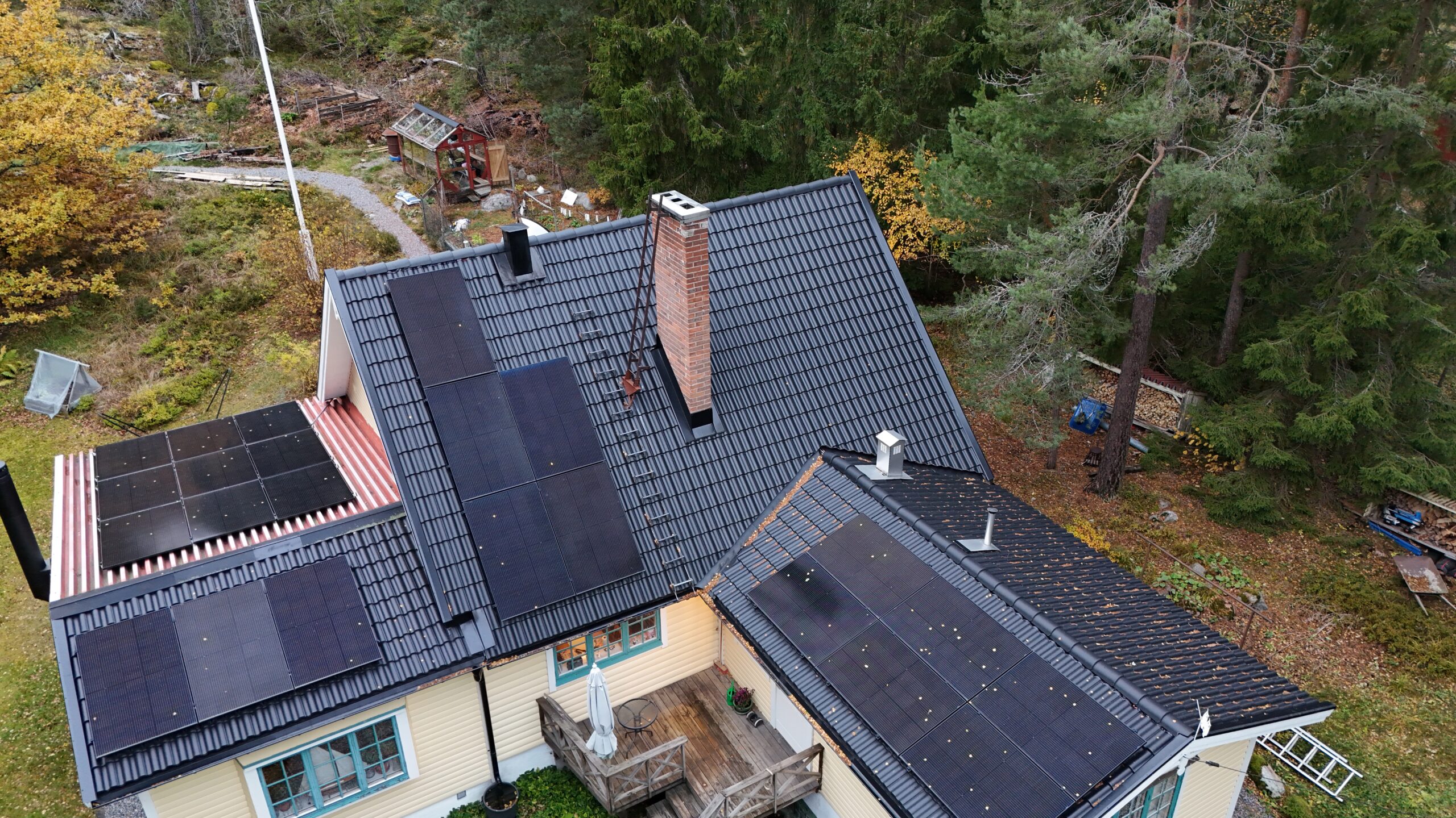 Fågelvy över ett villahus efter takomläggning med betongpannor och paneler av solceller. I bakgrunden syns tillhörande tomt.