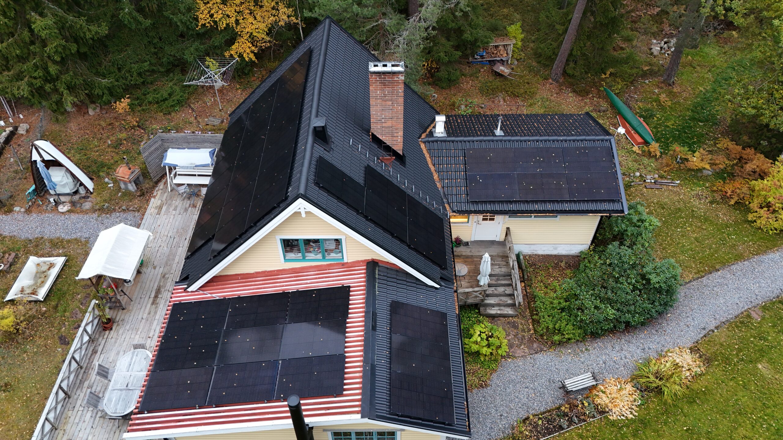 Fågelvy över ett villahus efter takomläggning med betongpannor och paneler av solceller. I bakgrunden syns tillhörande tomt.