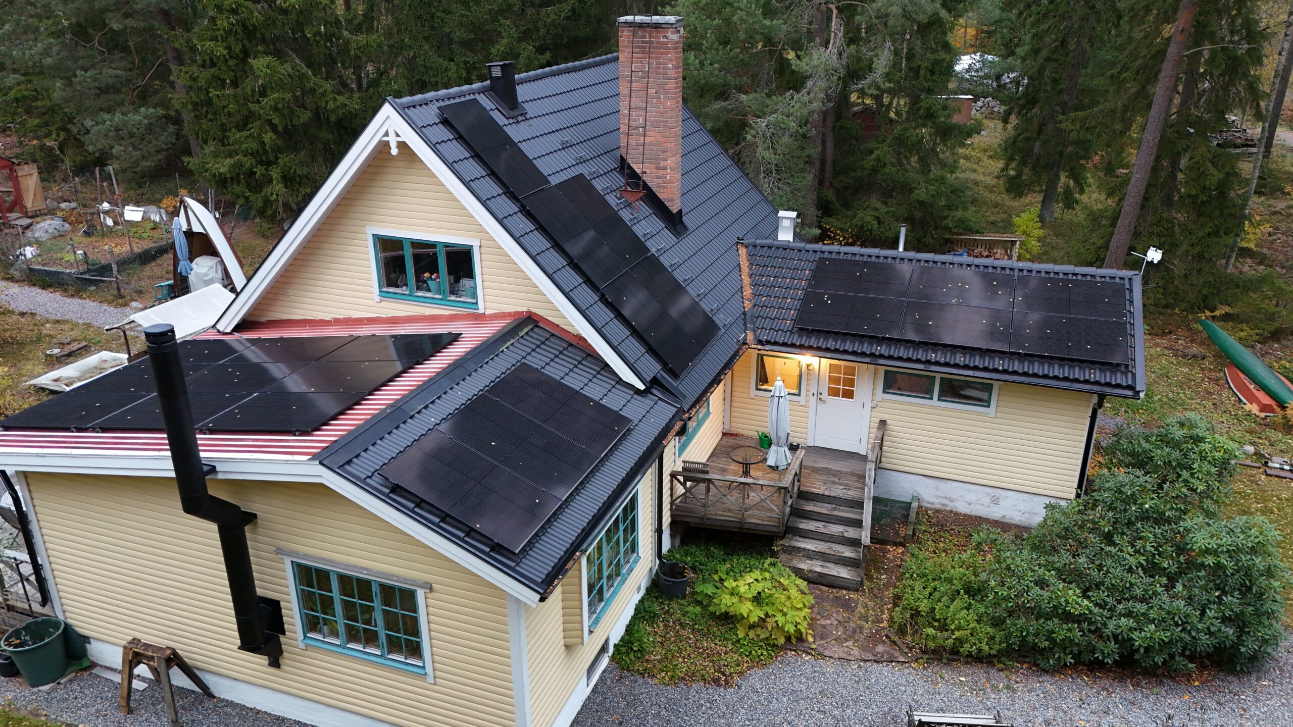 Fågelvy över ett villahus efter takomläggning med betongpannor och paneler av solceller. I bakgrunden syns tillhörande tomt.