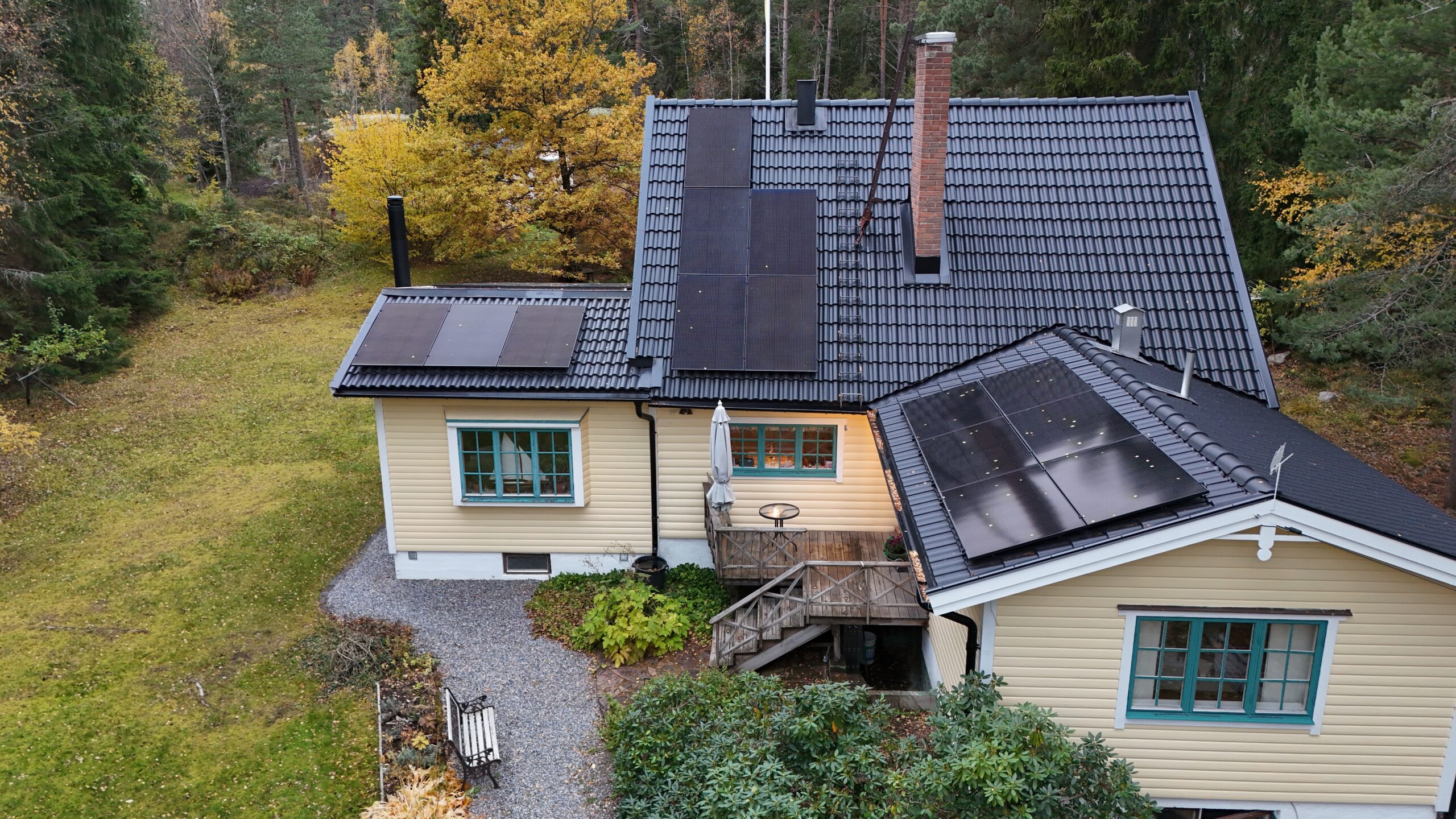 Fågelvy över ett villahus efter takomläggning med betongpannor och paneler av solceller. I bakgrunden syns tillhörande tomt.