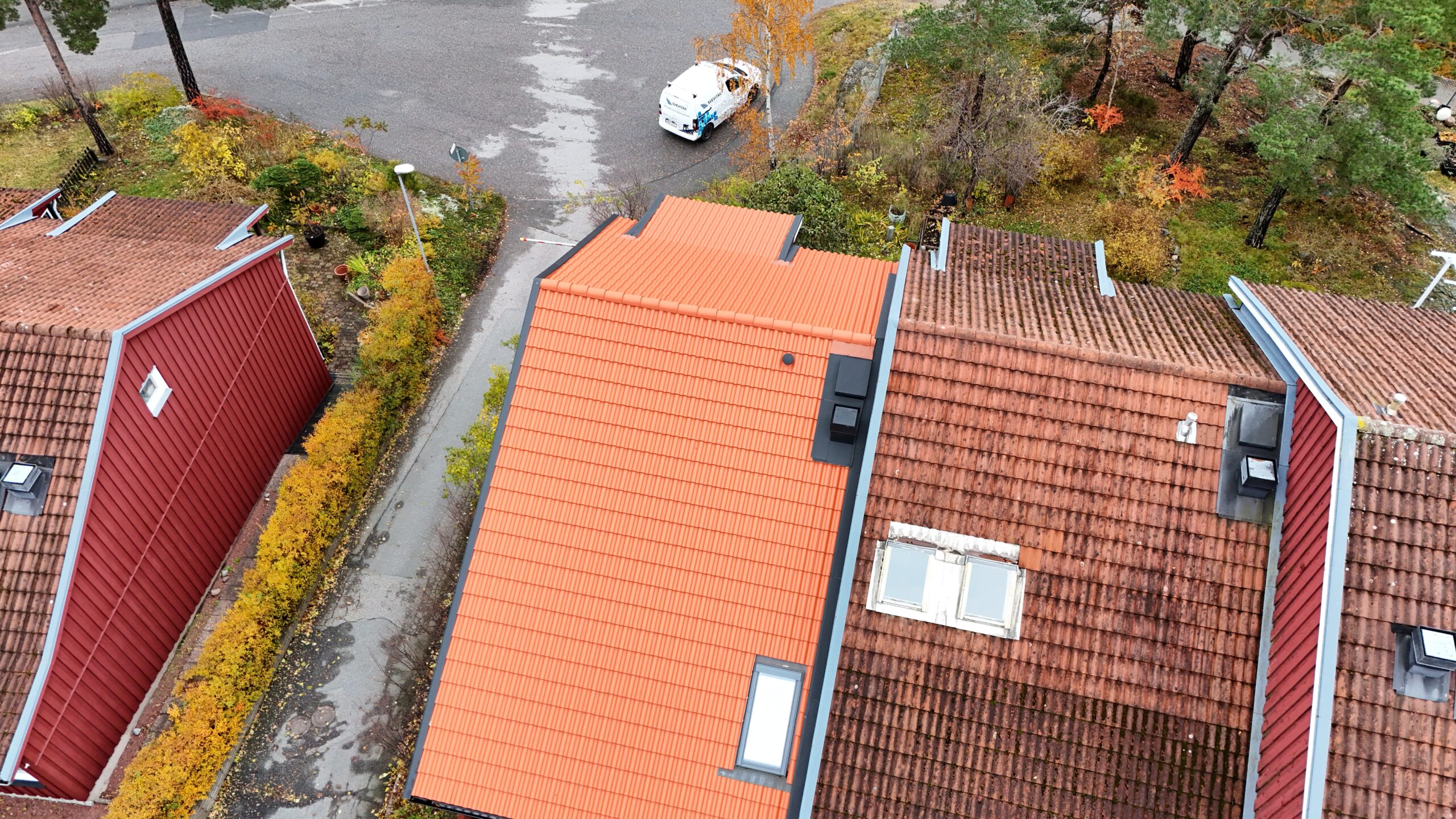 Fågelvy över taket på ett rött radhus och närliggande grannhus. Taket är sluttande med nylagda tegelpannor.