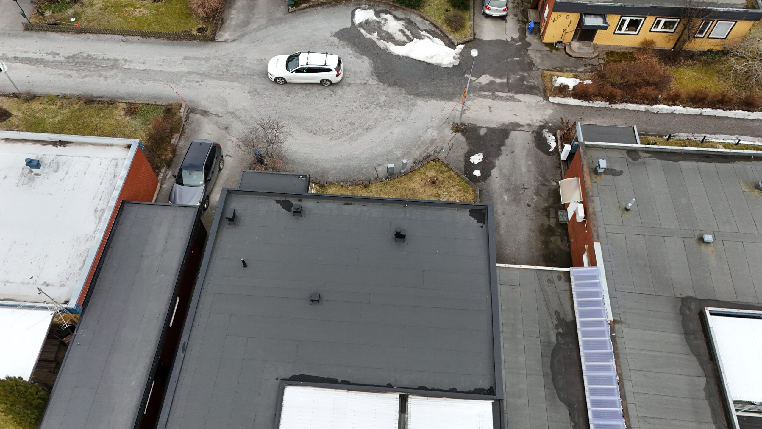 Fågelvy över på kedjehusets tak, efter takomläggning med asfaltpapp. Bredvid ligger grannhus.