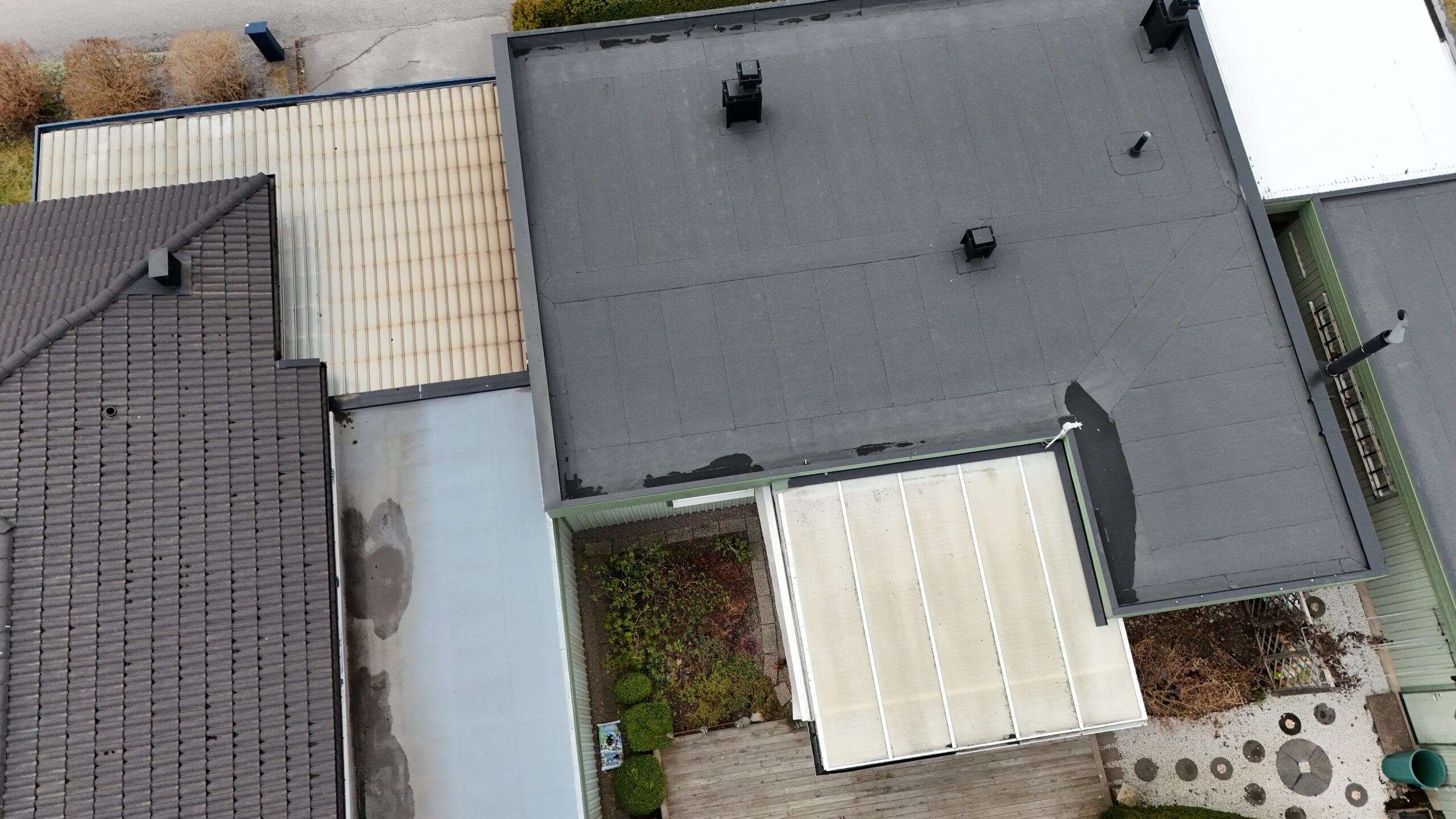 Fågelvy över kedjehus efter takomläggning med asfaltpapp. Runt huset ligger grannhus.