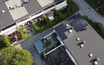 Ett radhusområde med platt papptak. På ett av husen sitter två paneler med solceller.