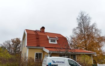 Gatuvy över en gul villa, med nylagt tegeltak. På taket finns en skorsten i tegel, snörasskydd samt en takstege.